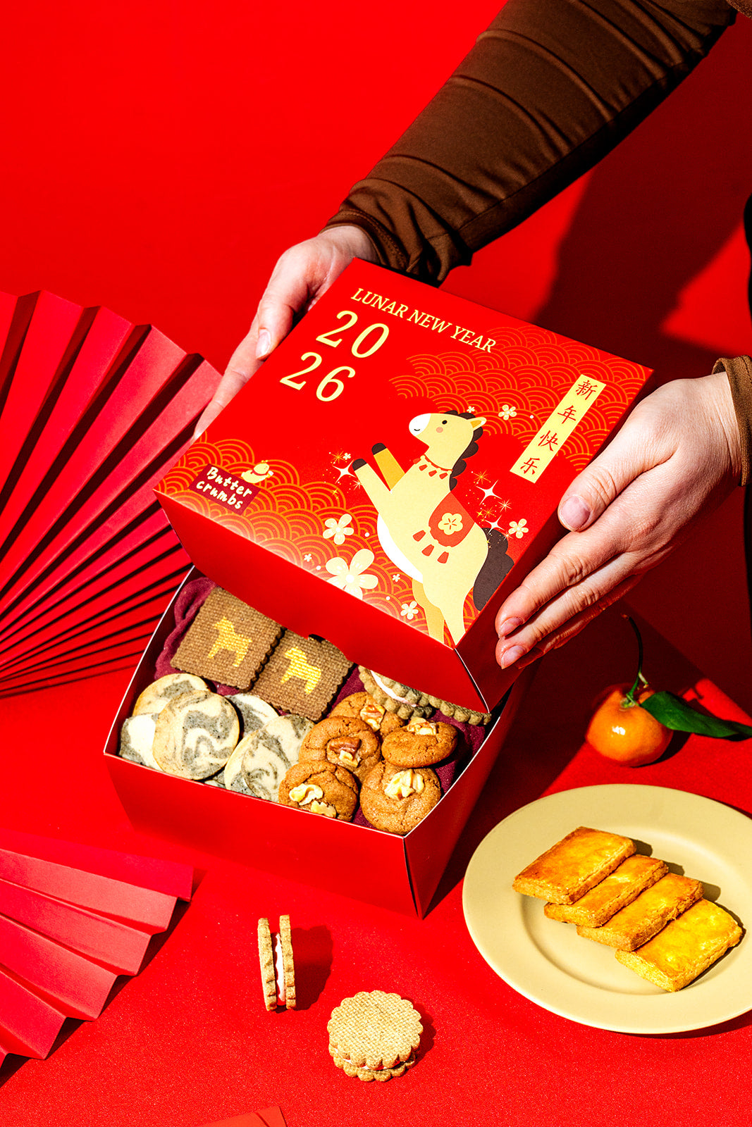 Red lunar new year cookie box with cookies and a plate of food on a red background